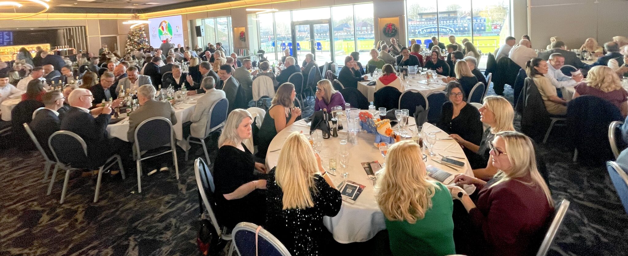 A busy event room filled with people seated at tables and talking