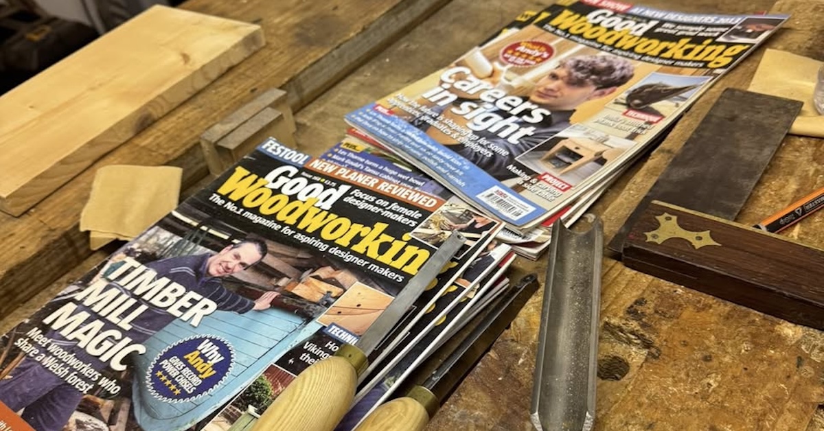 A selection of woodworking magazines and tools scattered on top of a wooden workbench